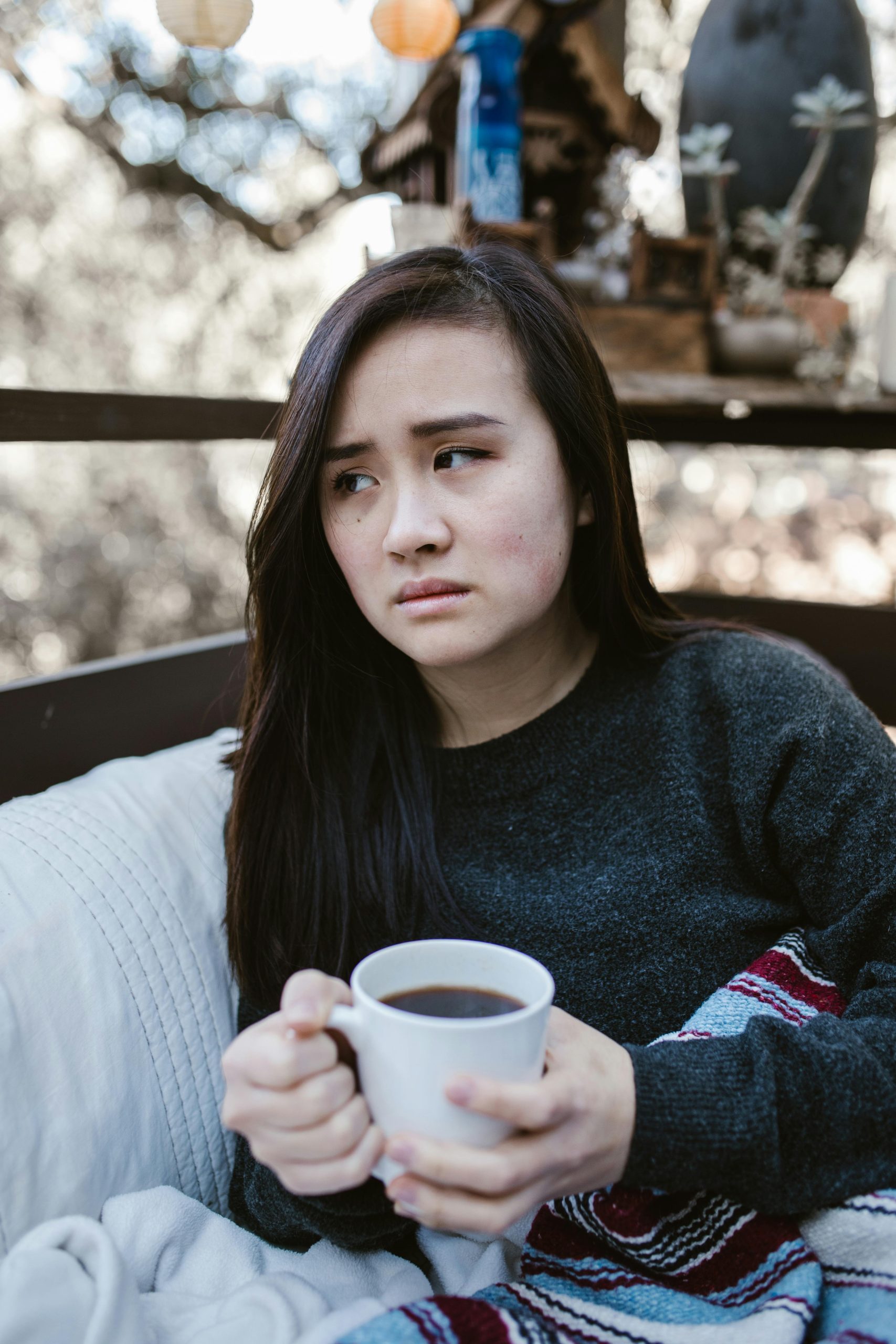 Thoughtful woman enjoying a warm drink outdoors on a chilly day.