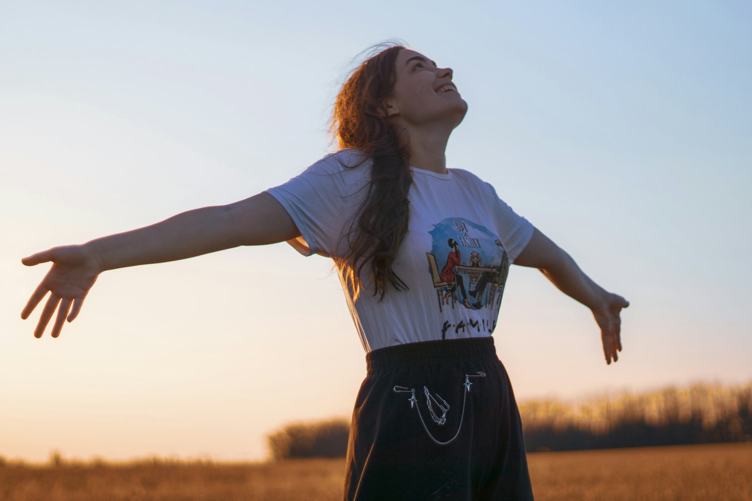 Femme aux bras ouverts vers la lumière du soleil dans un champ
