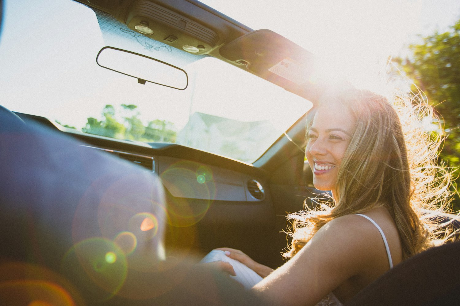 Femme qui rit dans une voiture baignée par la lumière du soleil