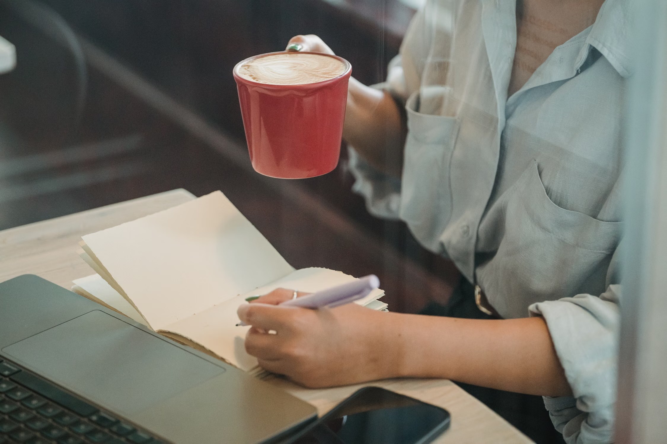 Femme écrivant dans un carnet au café pour prendre du recul