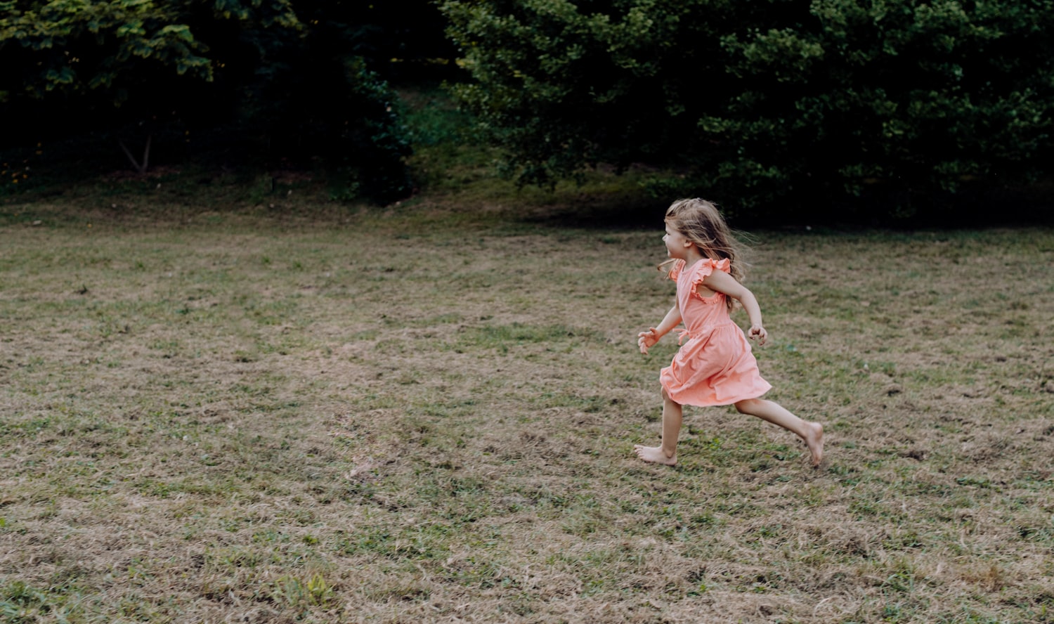 Une petite fille court pieds nus et libre dans un champ
