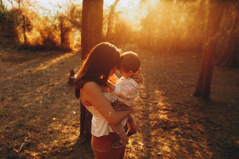 Une mère tient tendrement son enfant front contre front dans la lumière du soir