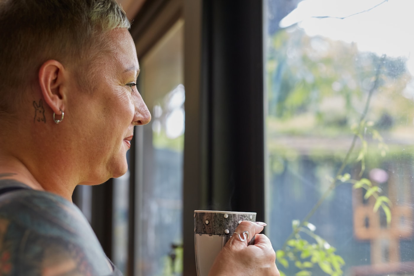 Une femme pensive tient une tasse et regarde par la fenêtre