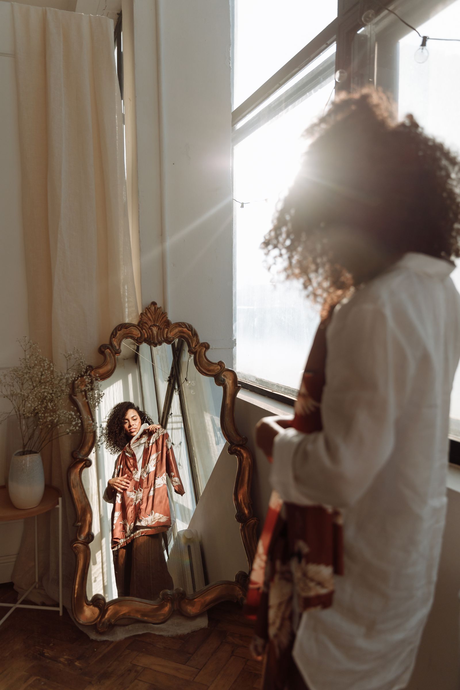 Femme tenant une chemise devant un miroir et choisissant sa tenue