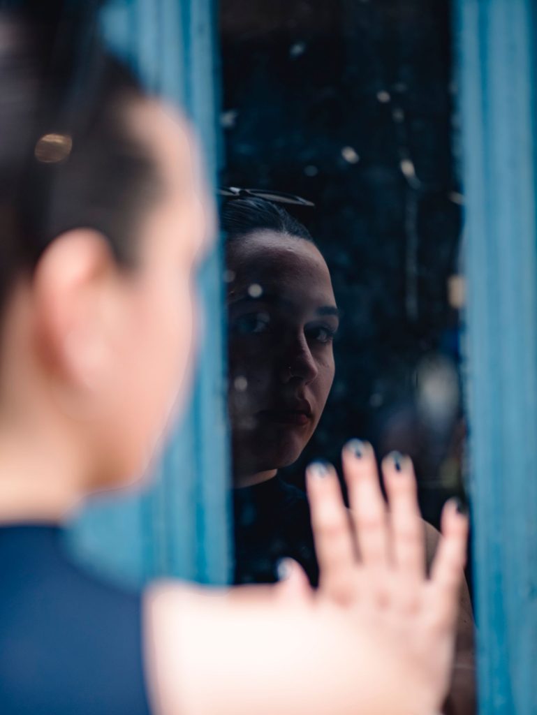 Femme pensive devant une fenêtre après une remarque blessante