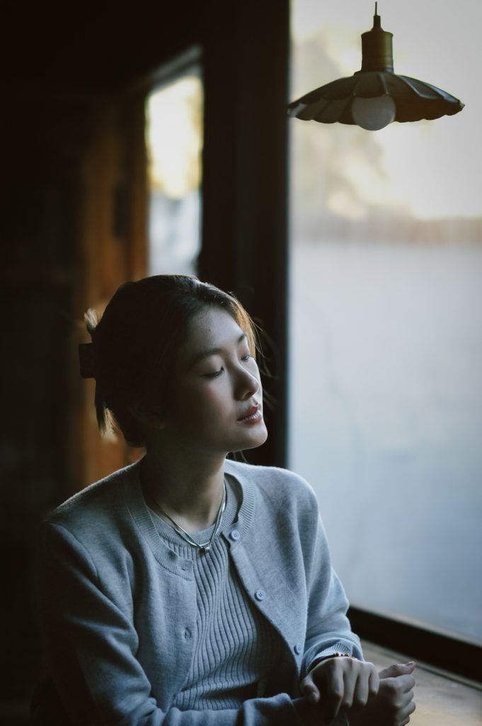 Femme assise près d’une fenêtre, prenant du recul sur sa dépendance affective
