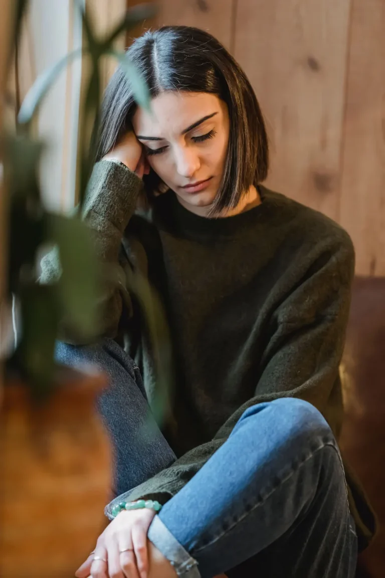 Femme fatiguée assise près d’une fenêtre pendant une période difficile