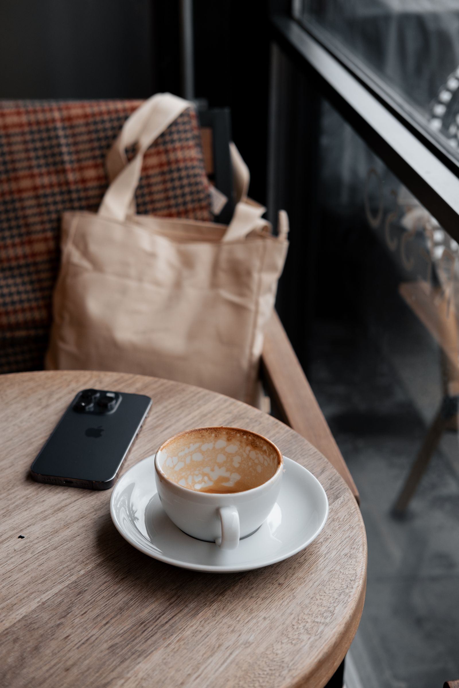 Téléphone posé près d’une tasse vide dans un café, symbole de l’attente