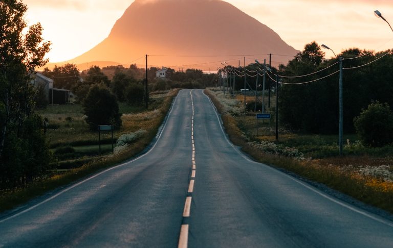 Une longue route vide vers une montagne au coucher du soleil